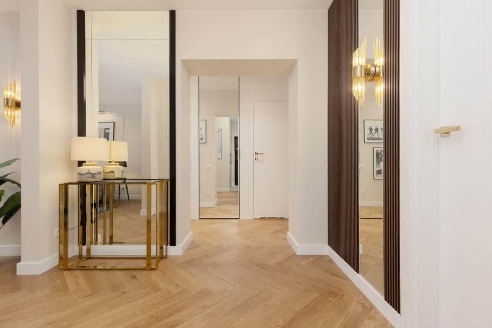 Elegant hallway with a gold console table, wall sconces, and a large mirror enhancing the space.
