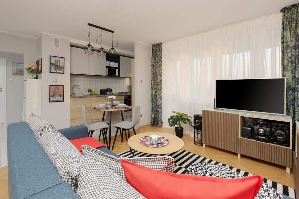 Living room with a fold-out corner sofa, coffee table, TV, closets, exit to balcony and dining area