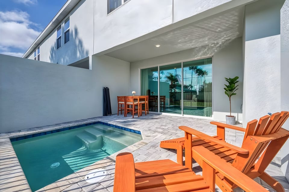 Step outside to your private oasis with a sparkling plunge pool and sleek stone tiles. Enjoy al fresco dining on the warm wooden patio set while tall palm trees sway gently, creating a truly tranquil atmosphere.