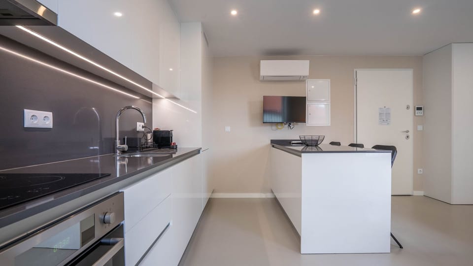 This open-plan space seamlessly combines a sleek kitchen with a compact living area, offering convenience and comfort for both cooking and unwinding after a day of exploration. Enjoy your favorite shows on the wall-mounted TV while preparing a meal.
