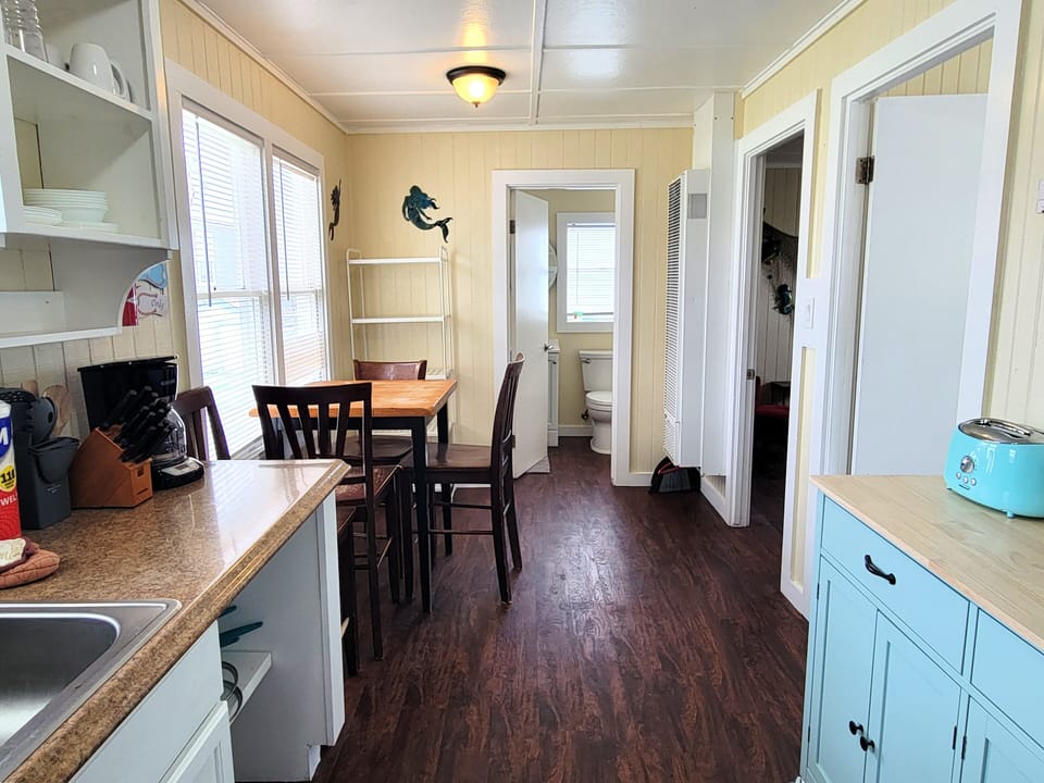 The main room has a kitchenette, dining area, and a cart for extra storage.