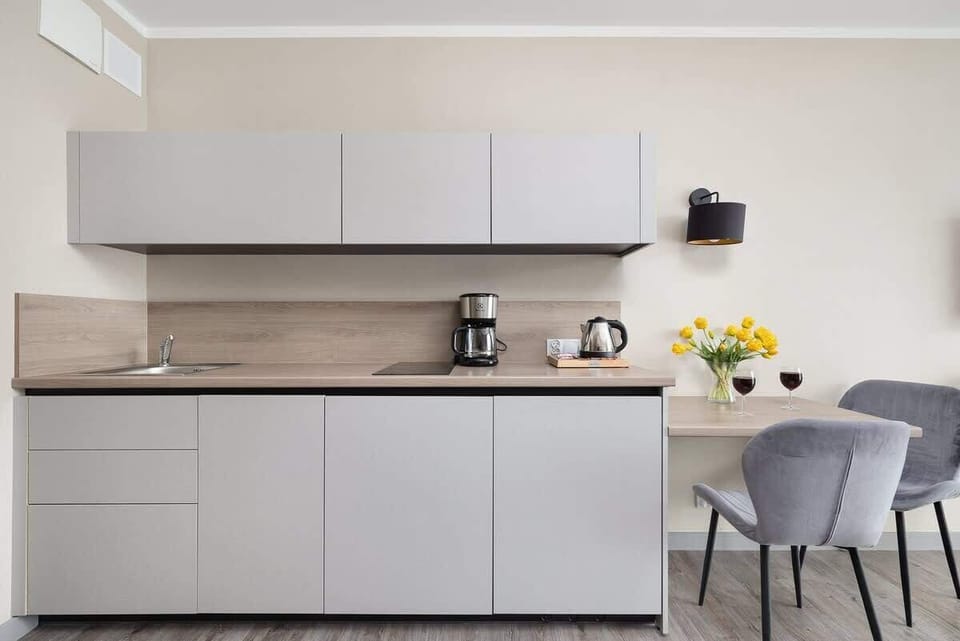 Kitchenette with minimalist cabinets, coffee maker, and yellow floral decoration.






