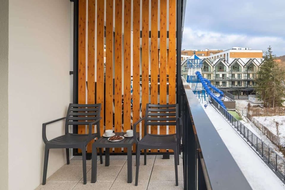 Balcony with chairs, wooden panels, and a winter cityscape view.
