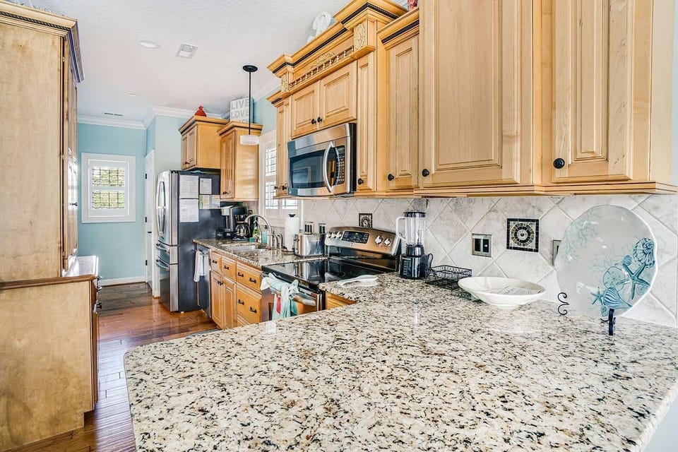 Sunlit kitchen with granite countertops and warm wood cabinets