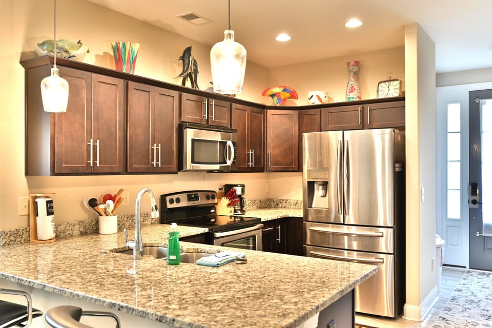 Modern kitchen with granite, dark wood, stainless steel & artistic decor.