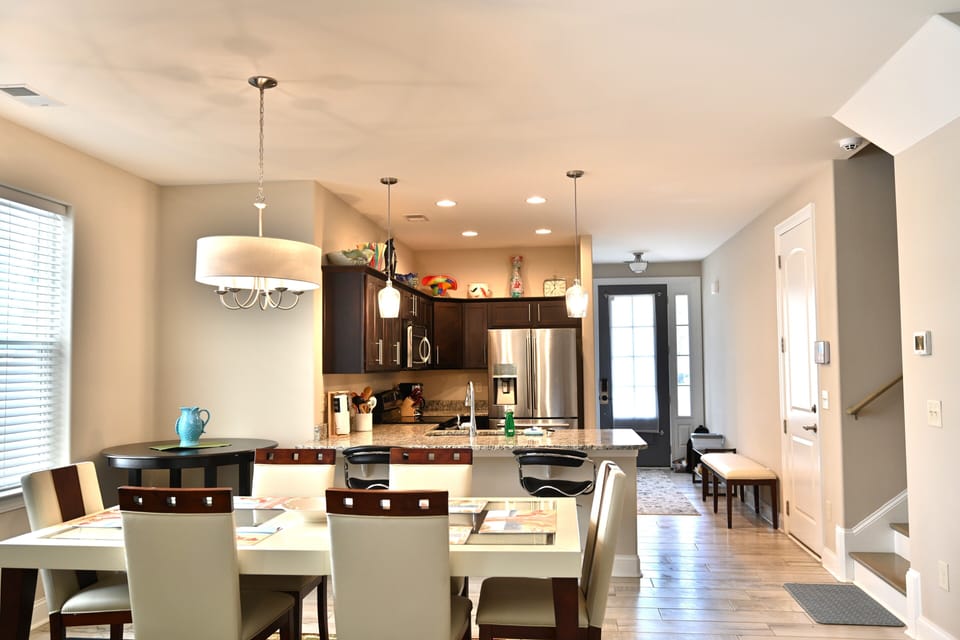 Open dining & kitchen with sleek decor, dark wood, & stainless appliances