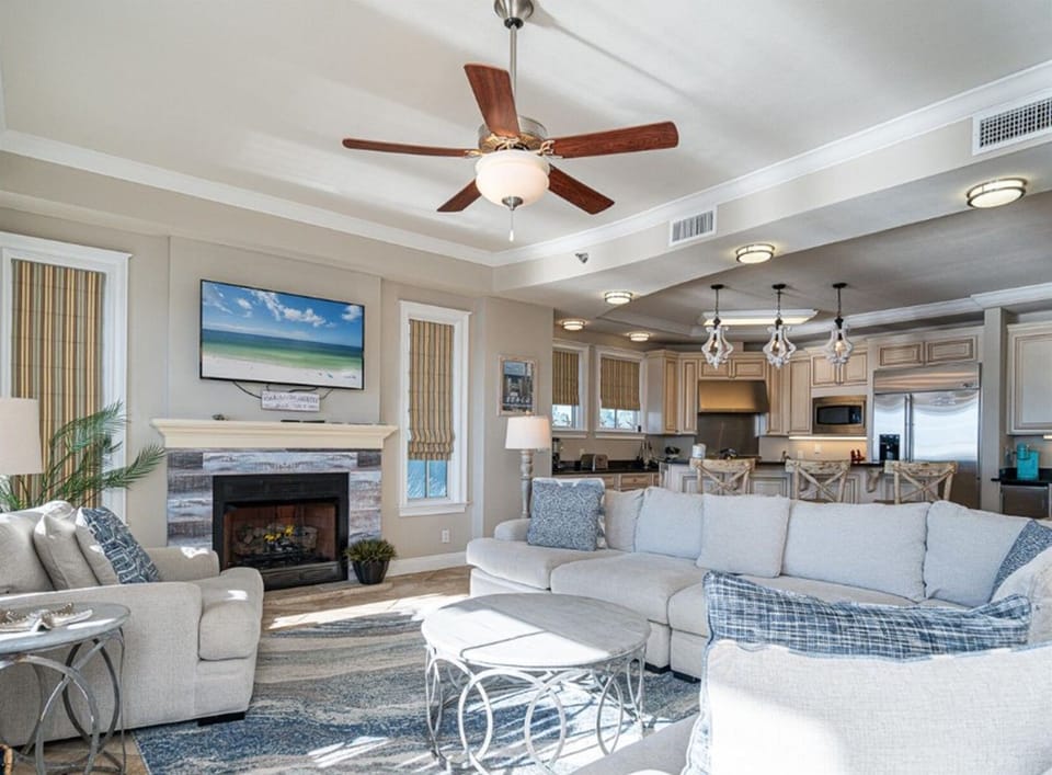 Relax in your elegant open-plan space with cozy fireplace, modern kitchen, and coastal-inspired décor perfect for family gatherings.
