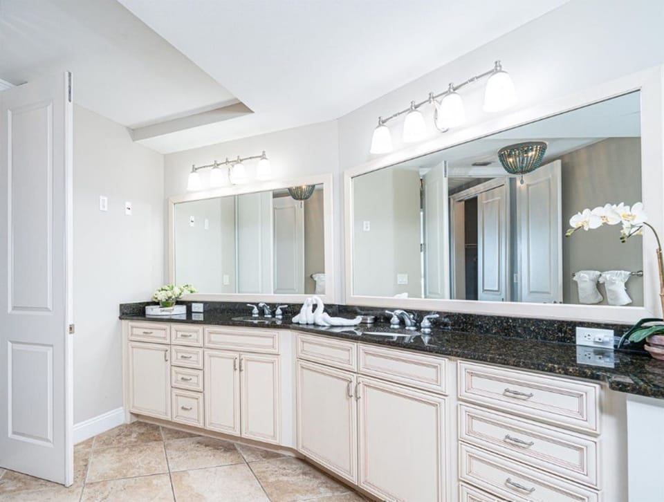 Your elegant dual-vanity bathroom features granite countertops, crisp white cabinetry, and abundant natural light for your morning routine.
