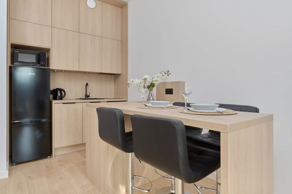 Kitchenette with wooden cabinets, black appliances, and dining area.
