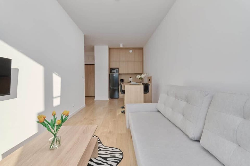 Living room with gray sofa, light wooden floor, and minimalist design.

