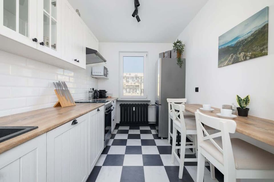 Kitchen with checkered floor, white cabinets, and a cozy dining area.
