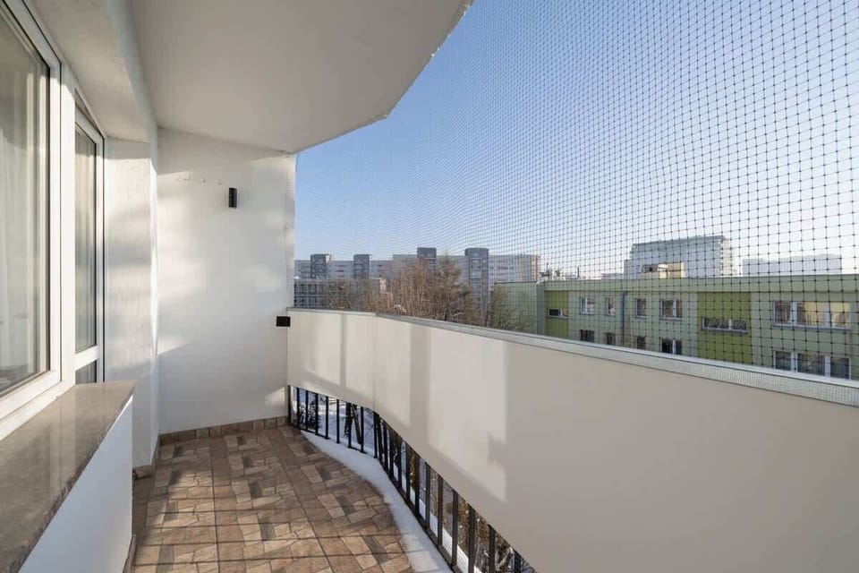Balcony with curved railing, city view, and a cozy seating area.
