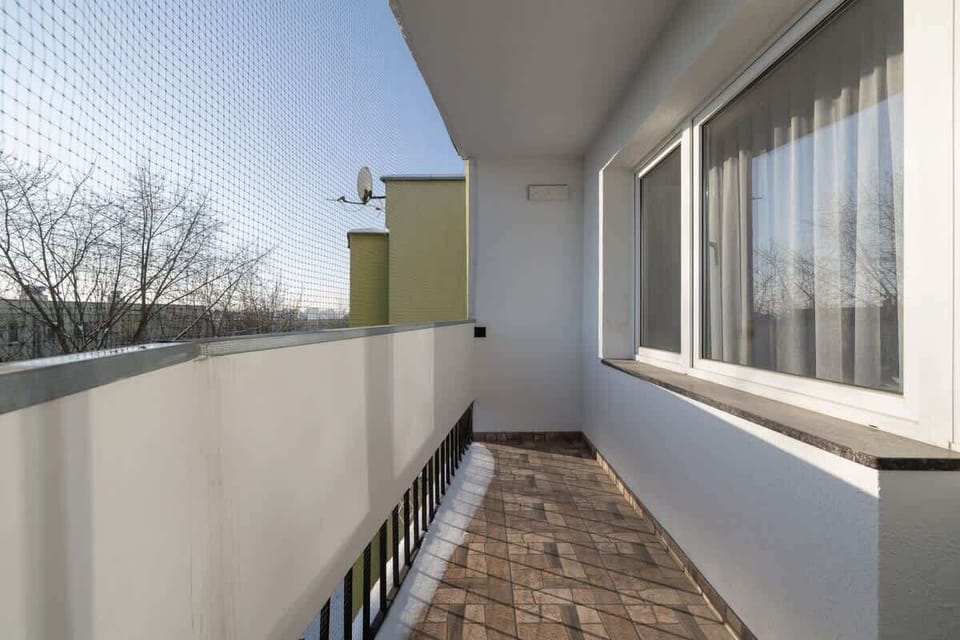 Balcony with curved railing, city view, and tiled flooring.

