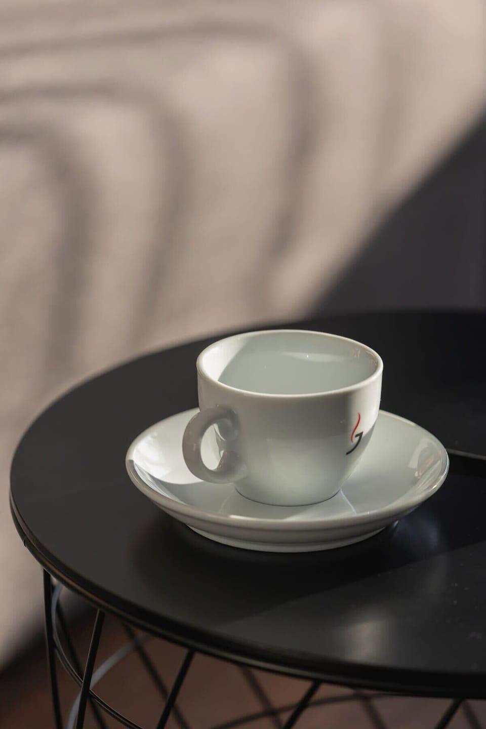 Close-up of a coffee cup on a modern metal table.
