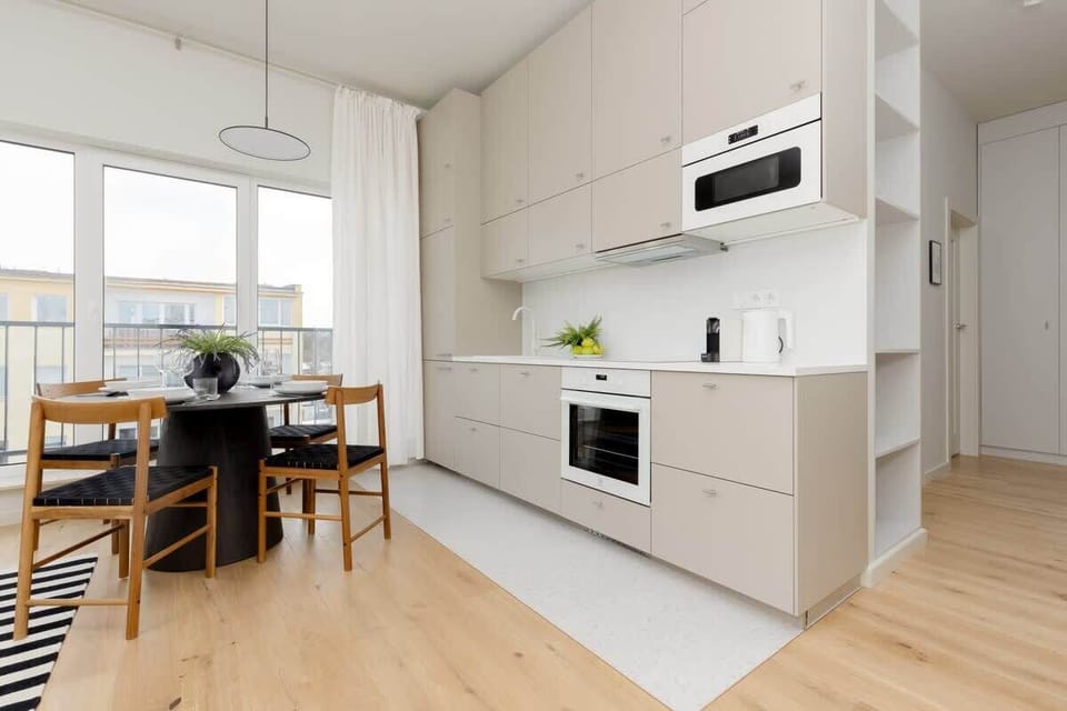Kitchen area featuring white cabinets, built-in oven, and a compact wooden dining table.
