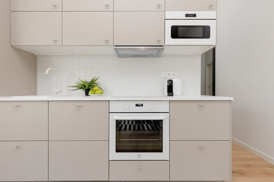 Kitchen area featuring white cabinets, built-in oven, and a compact wooden dining table.
