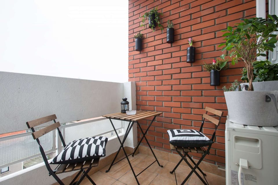 Terrace with table and chairs and flowers on the red brick wall.