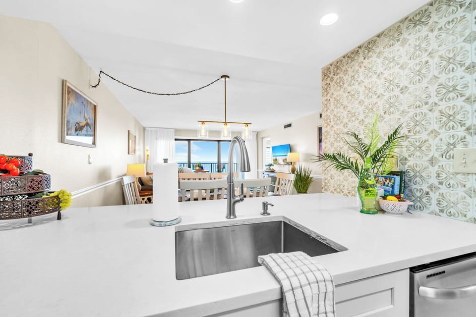 Cook with ease in this bright, modern kitchen featuring quartz countertops, stylish backsplash, and stunning gulf views.