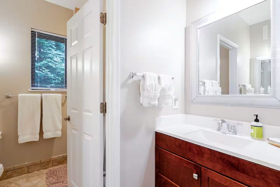 Split bathroom with two sinks separated from the toilet and tub room