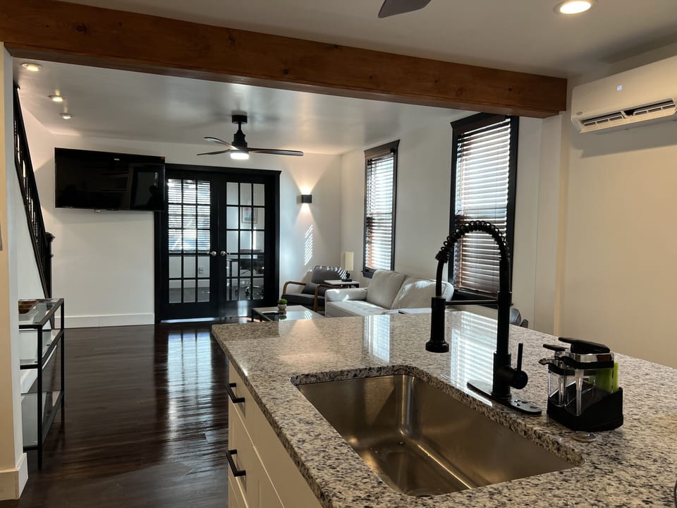 Modern open concept kitchen, living room, and office with double French doors.