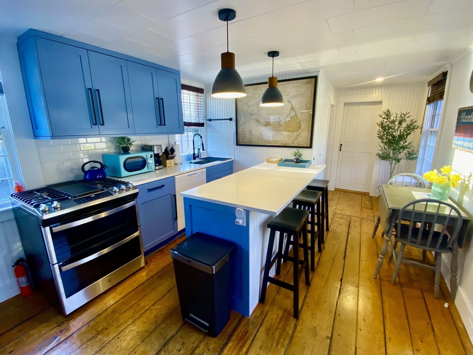 Fully renovated kitchen with wide plank, pine floors, and quartzite countertops.