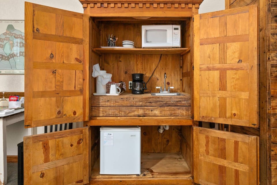 Discover hidden culinary convenience with the charming kitchenette discreetly tucked away in an armoire, providing all the essentials.