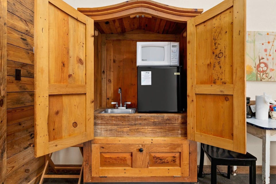 Discover hidden culinary convenience with the charming kitchenette discreetly tucked away in an armoire, providing all the essentials.