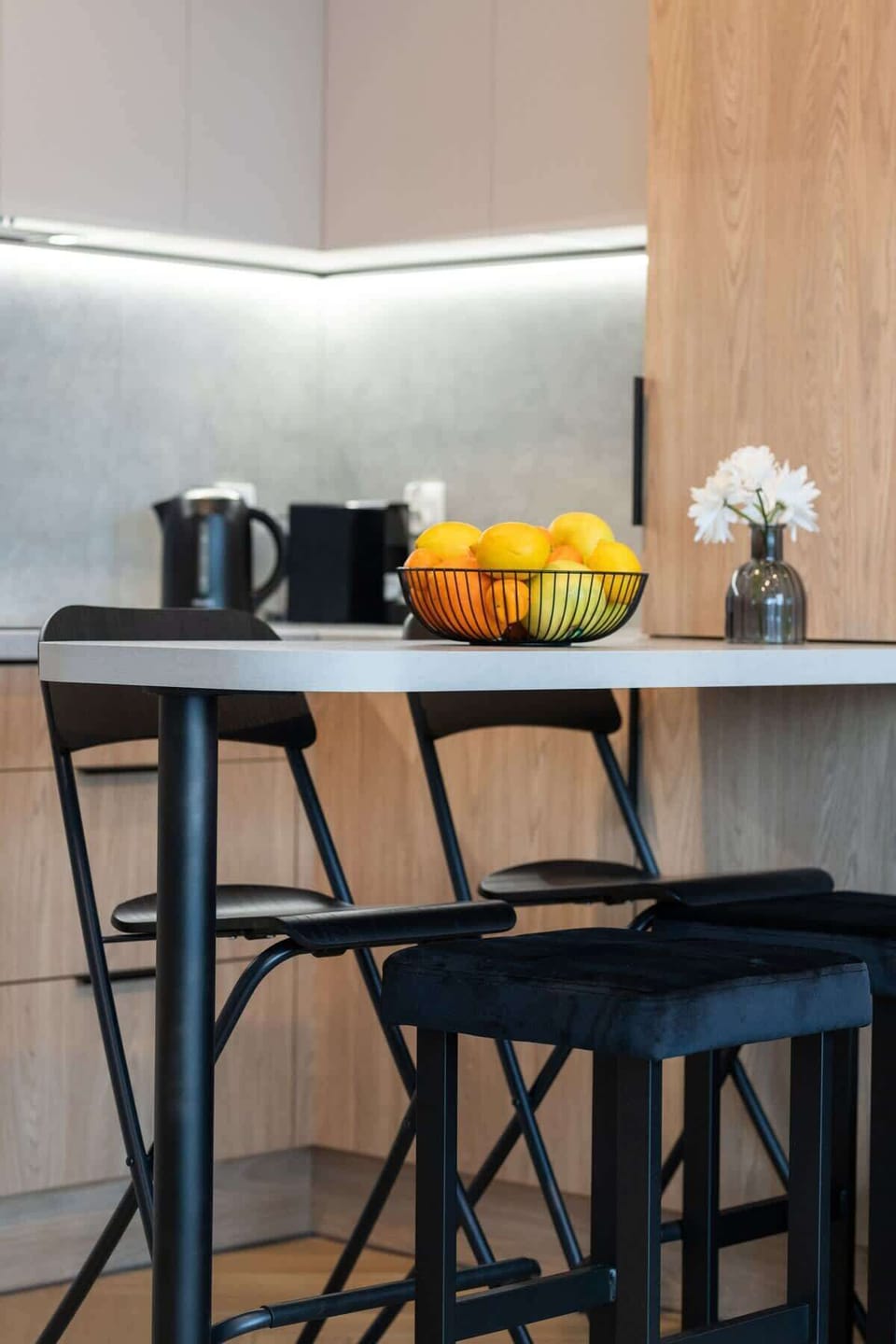 Compact dining area with black bar stools and under-cabinet lighting.
