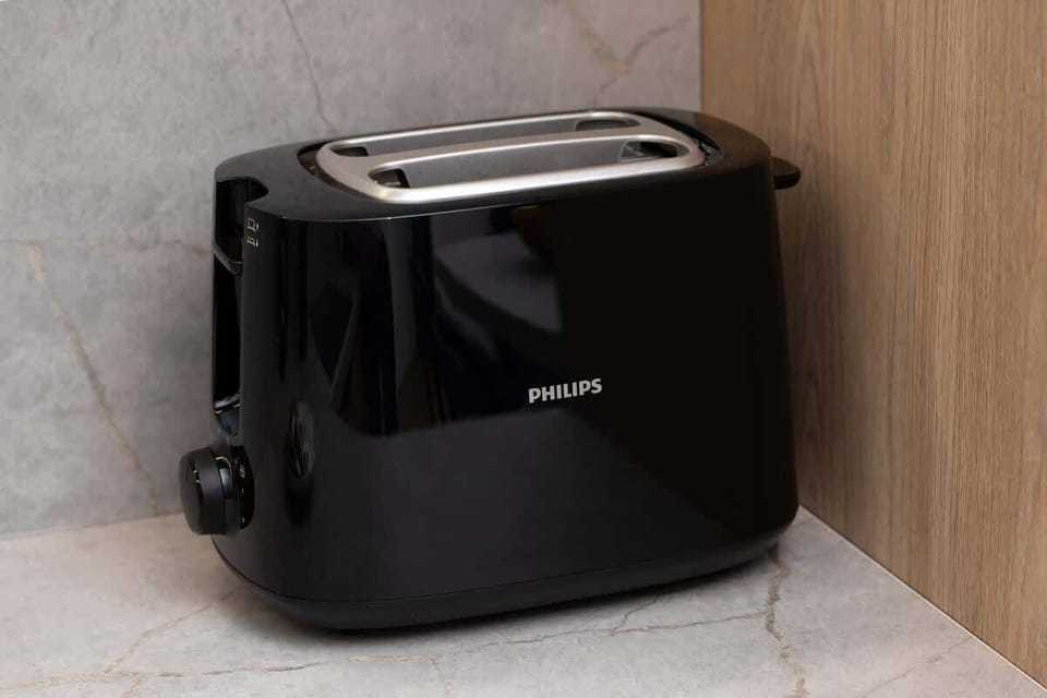 Black toaster on a light wooden kitchen counter.
