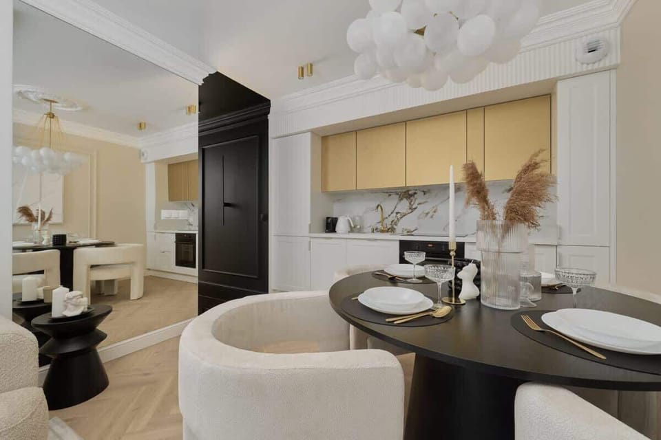 Dining area with round table, white chairs, and modern chandelier.
