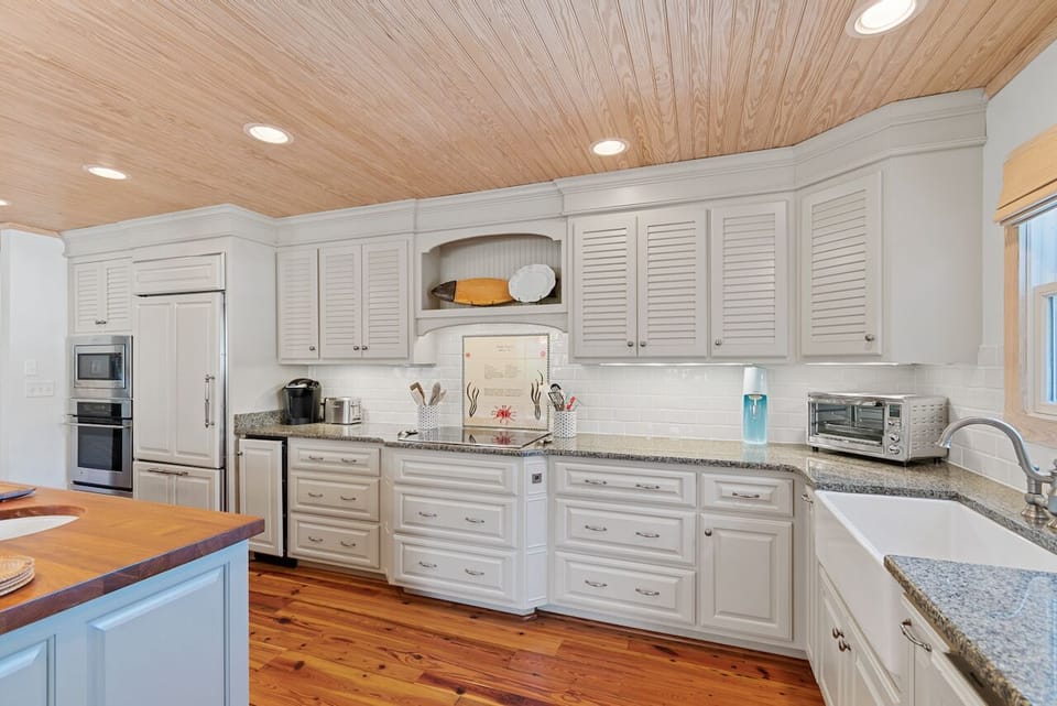 Step into your gourmet kitchen with gleaming white cabinetry, granite counters, and warm wood ceiling—perfect for creating memorable meals together.