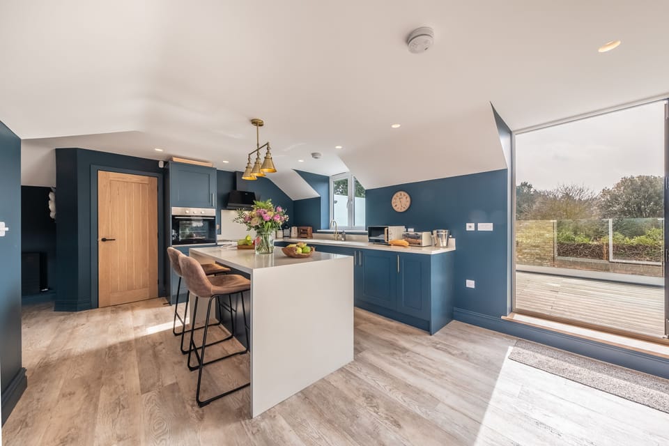 First floor: Bright modern kitchen opening onto rooftop balcony