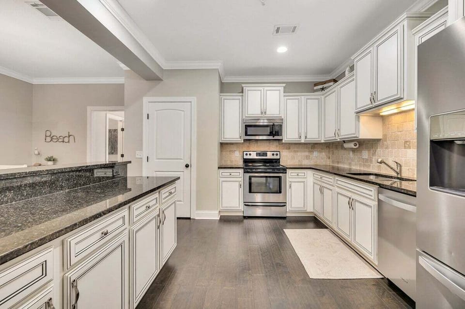 White kitchen with dark granite counters and stainless appliances