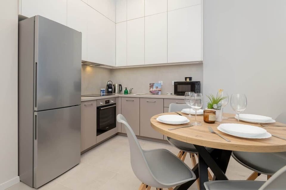 Kitchen with stainless steel fridge, white cabinets, and modern decor.

