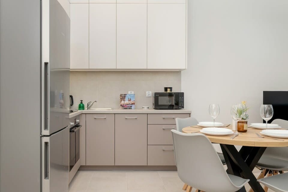Compact kitchen with white cabinets, dining area, and modern appliances.
