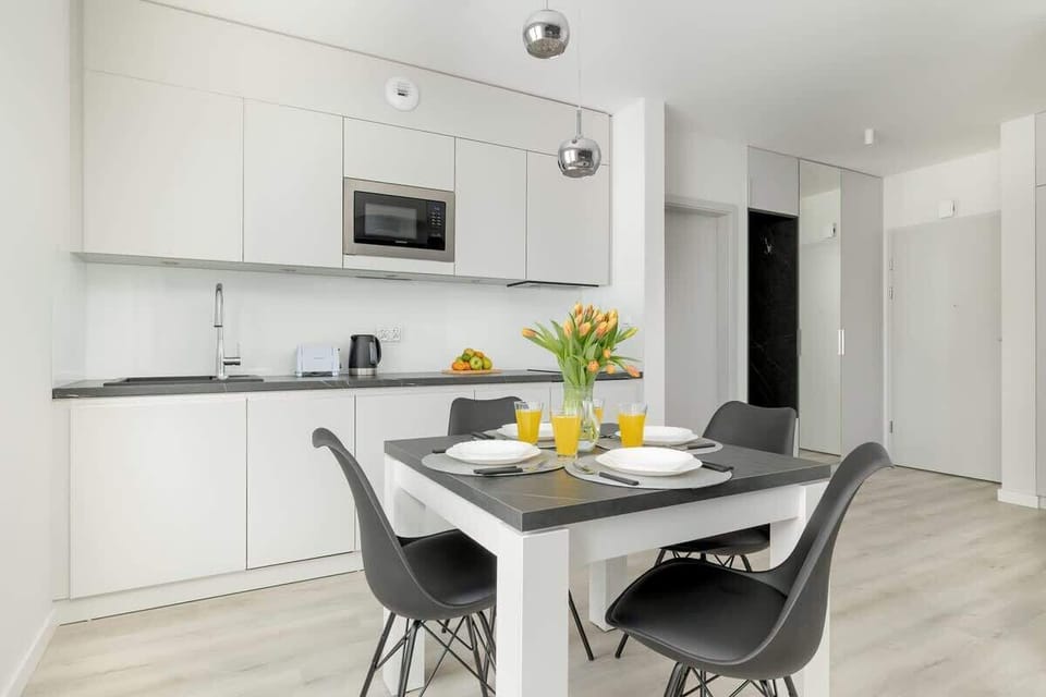 Kitchen with sleek white cabinetry, built-in appliances, and a breakfast bar.
