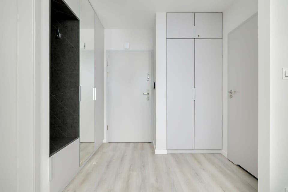Hallway with light wooden flooring, white doors, and minimalist design.
