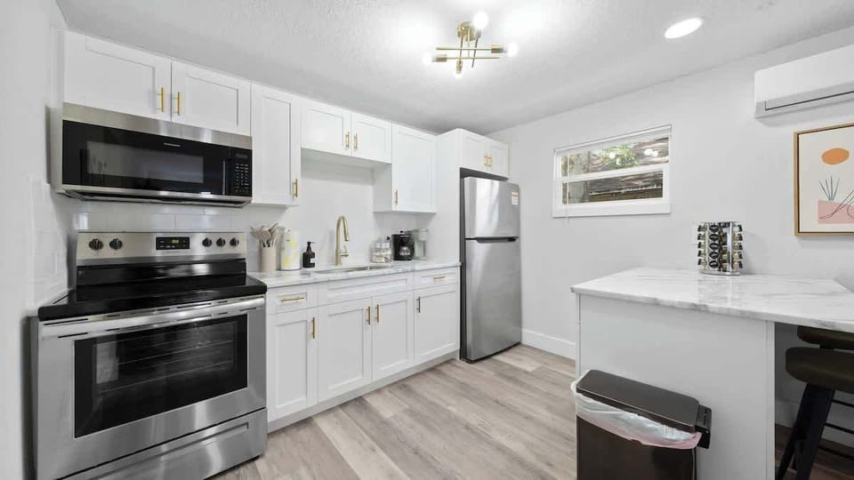 Fully equipped kitchen featuring a sleek marble island, stocked spice rack, high-end ceramic cookware, and all the essentials—full-size fridge, stove, oven, microwave, toaster, and blender—ready for your culinary creations