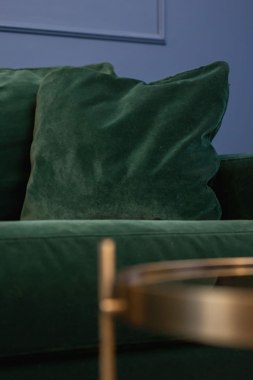 Close-up of a luxurious green velvet cushion on a gold-trimmed chair.






