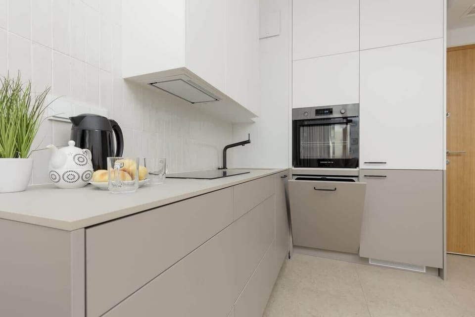 Kitchenette with an induction hob, refrigerator with freezer, oven, dishwasher, electric kettle and dining area.