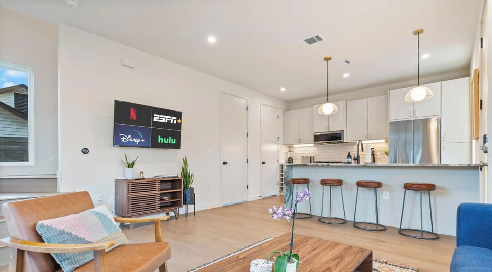 Light-filled open living area with a comfy lounge setup, streaming-ready TV, and a spacious kitchen island.