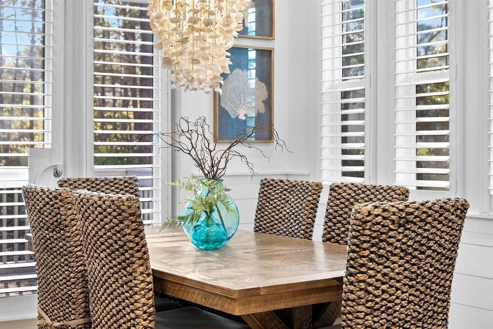 A dining area with large windows, a modern chandelier, and an inviting table setup.
