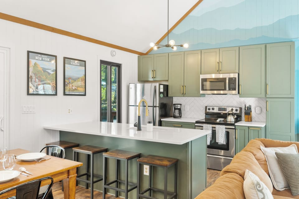 Stylish sage kitchen with island, vaulted ceiling, and seating for 4