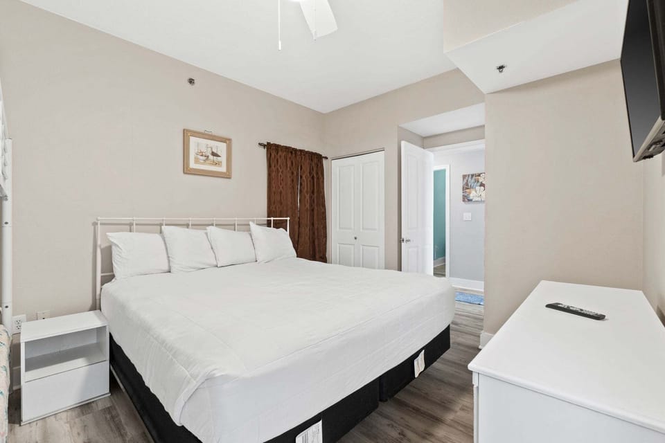 A mounted TV provides easy entertainment, and the room includes a dresser for convenient storage.