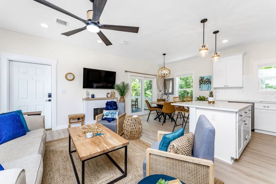Open living, dining, and kitchen area with comfortable seating, queen sofa sleeper, Roku TV, electric fireplace, and a fully equipped kitchen with bar seating.