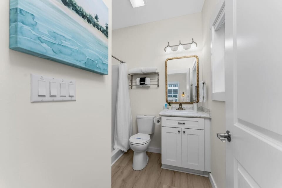 Bright ensuite bathroom off the primary bedroom featuring a walk in shower, coastal décor, vanity with storage, and fresh towels for a clean and comfortable space.