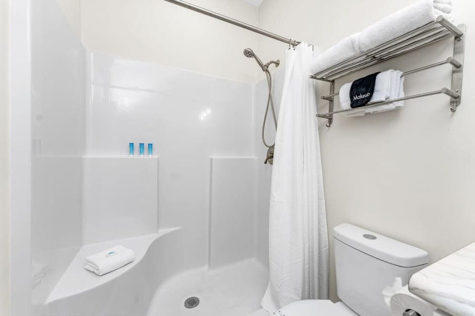 Walk in shower in the primary ensuite bathroom featuring built in shelving, fresh towels, and essential toiletries for a comfortable stay.
