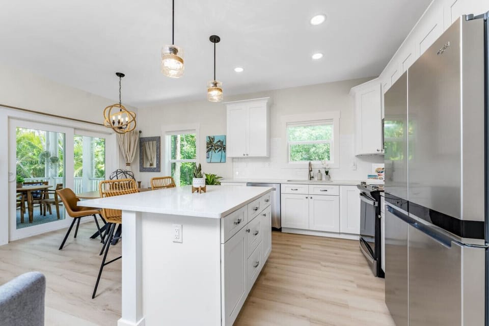 Fully equipped kitchen with large island, stainless steel appliances, and open flow to the dining area and screened patio.