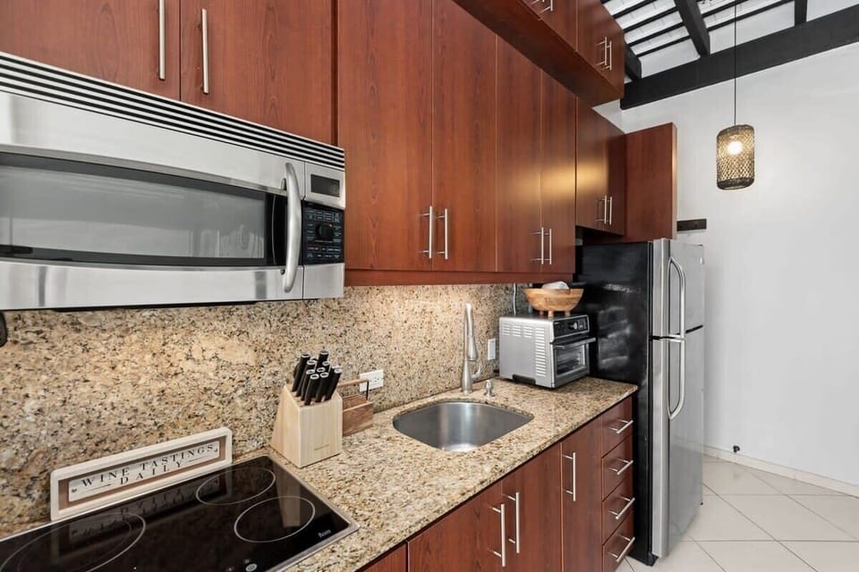 The kitchen is simple yet modern and features a fridge, a microwave, a toaster oven/air fryer combo, a coffee maker, a sink, and a 4-burner stove