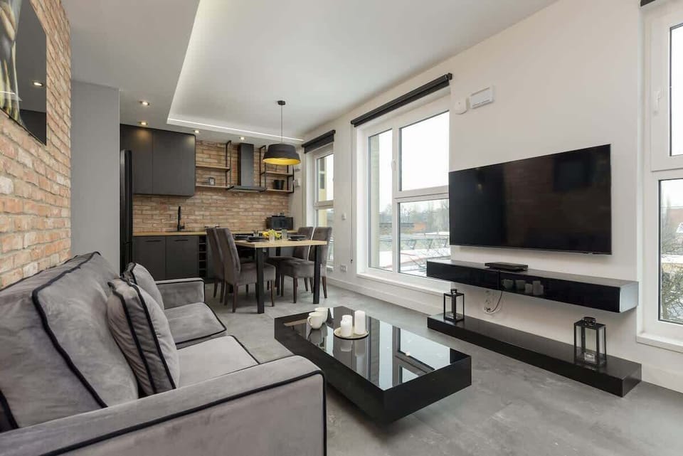 Open-plan space combining a chic dining area, dark kitchen cabinetry, and soft lighting.
